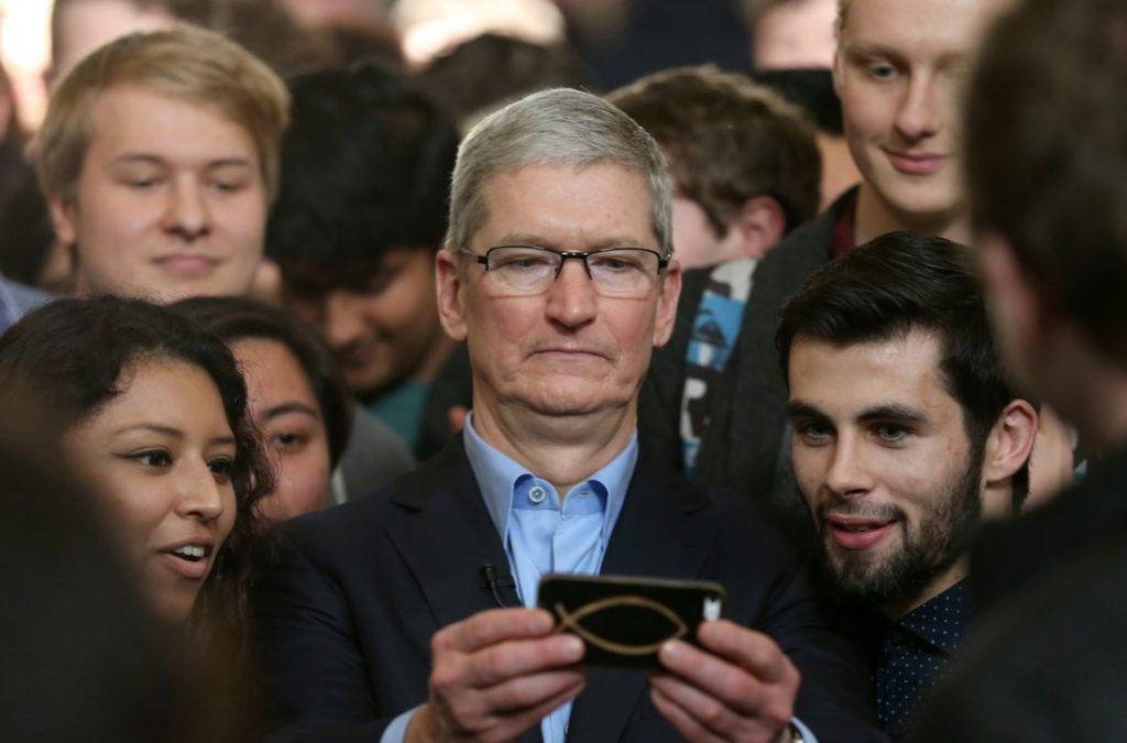 Apple CEO Tim Cook with a mobile phone and people around him