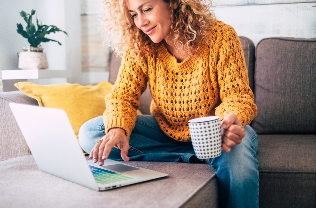 Woman using computer while drinking from a mug