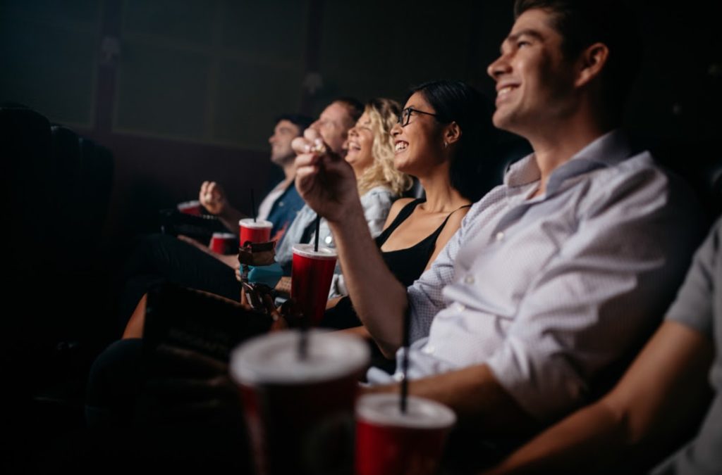 People in movie theater with popcorn and drinks