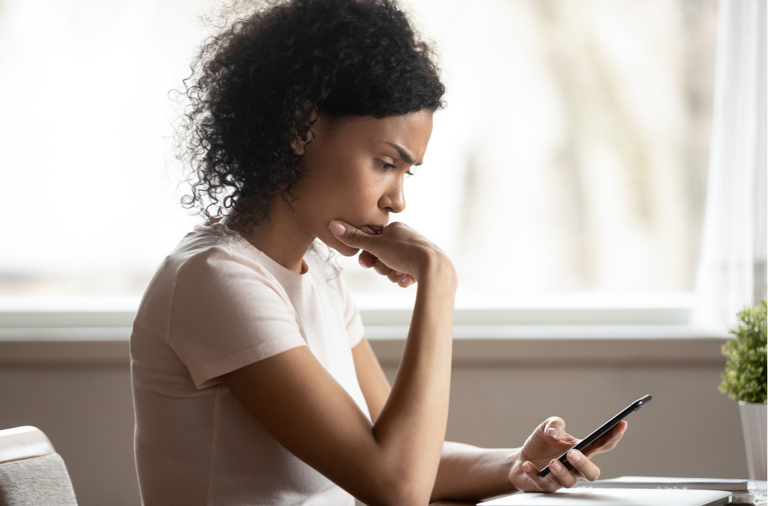 Pensive woman looking at mobile phone