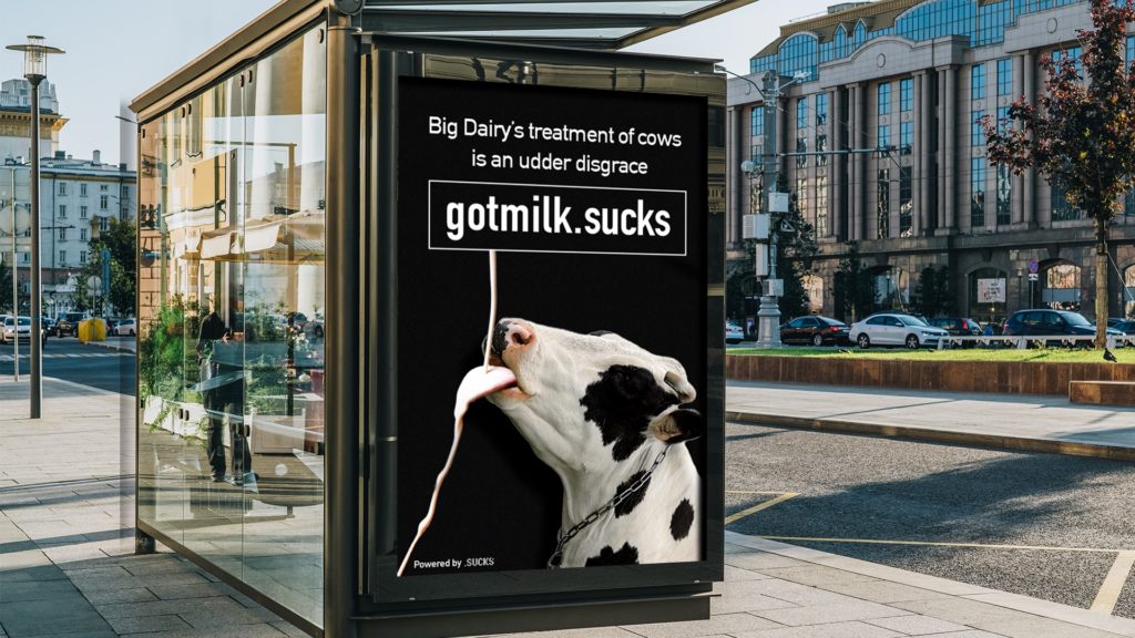Billboard featuring cow drinking cow mlik with "gotmilk.sucks" and "Big Dairy's treatment of cows is an udder disgrace"